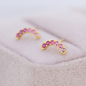 Peut inclure: Une paire de boucles d'oreilles en or avec une forme incurvée et des pierres précieuses roses. Les boucles d'oreilles sont serties dans un sertissage en or et ont une finition polie.