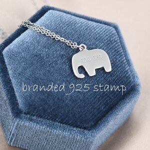 May include: A silver elephant pendant necklace with a 925 stamp on the back. The necklace is displayed in a blue velvet box.