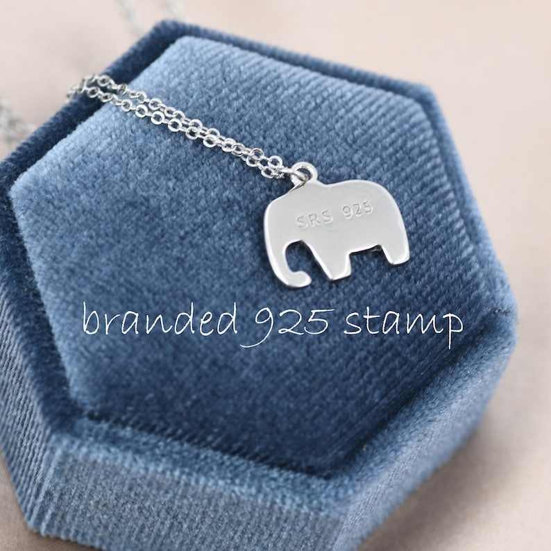 May include: A silver elephant pendant necklace with a 925 stamp on the back. The necklace is displayed in a blue velvet box.