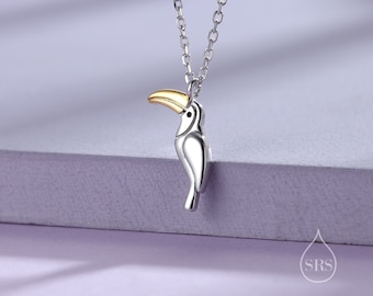 Puede incluir: Collar de tucán de plata con pico dorado. El tucán está posado en una cadena de plata.