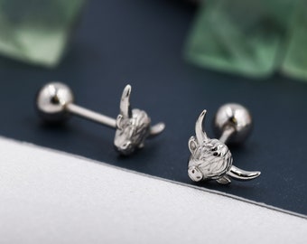 May include: A pair of silver-toned metal stud earrings featuring a detailed, textured Highland cow head design. Each earring has a smooth, round ball backing attached to a straight post, creating a secure closure for these animal-themed accessories.