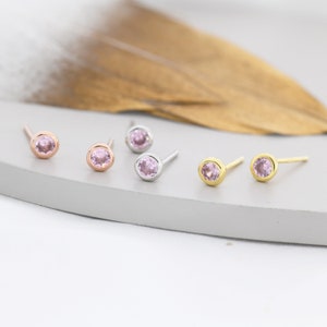 Peut inclure: Trois paires de petites boucles d'oreilles à clous avec des pierres précieuses roses. Les boucles d'oreilles sont en argent, en or rose et en or.