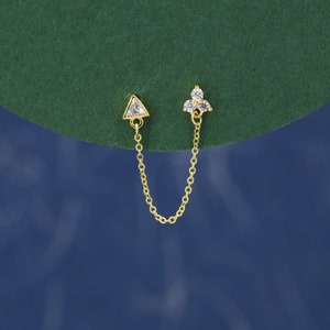 Peut inclure: Une paire de boucles d'oreilles en or avec une chaîne reliant une boucle d'oreille en forme de triangle à une boucle d'oreille en grappe à trois pierres.