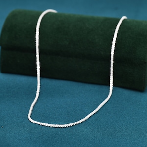 Puede incluir: Un collar de cadena de plata sobre un fondo de terciopelo verde.