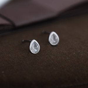以下が含まれることがあります： クリアな宝石が付いたシルバーの涙型のイヤリングのペア