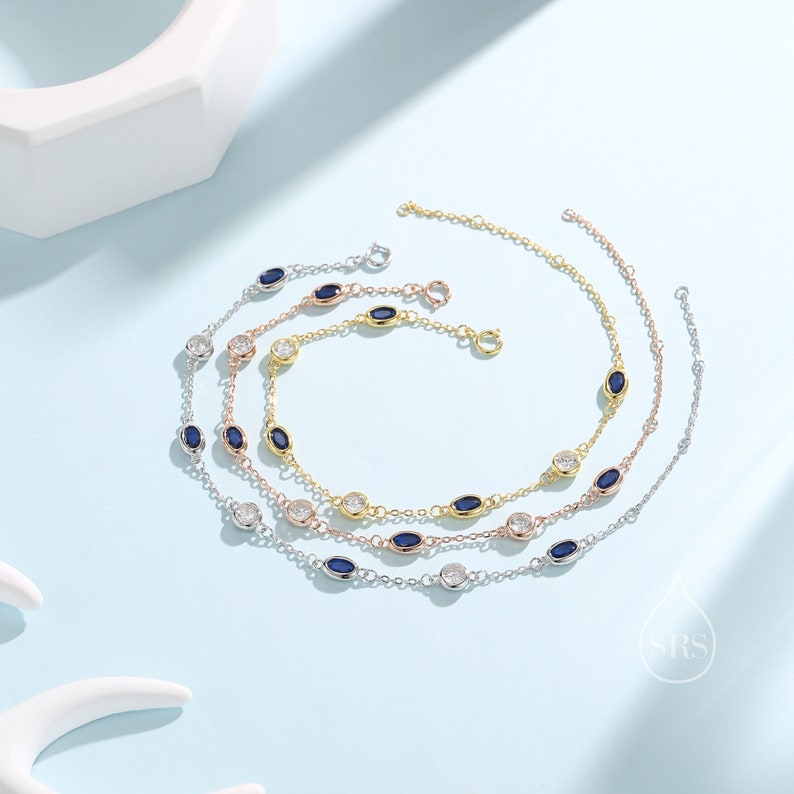 Peut inclure: Trois bracelets en argent, or et or rose avec des pierres pr&eacute;cieuses bleues et claires de forme ovale. Chaque bracelet a une cha&icirc;ne d&eacute;licate et un fermoir &agrave; ressort.