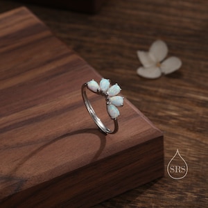 Puede incluir: Un anillo de plata con un grupo de piedras de ópalo blanco en forma de flor.