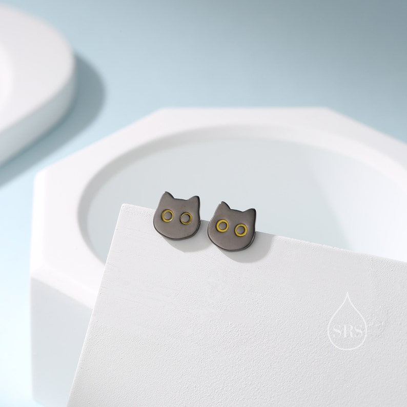 Peut inclure: Une paire de boucles d'oreilles clous en forme de chat noir avec des accents dor&eacute;s. Les boucles d'oreilles sont petites et d&eacute;licates, et elles seraient un excellent cadeau pour tout amateur de chats.