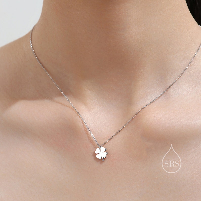 May include: A silver necklace with a four-leaf clover pendant.