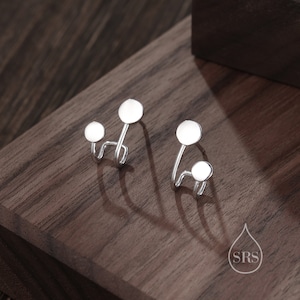 Peut inclure: Une paire de boucles d'oreilles en argent avec deux disques ronds sur chaque boucle d'oreille. Les boucles d'oreilles sont conçues pour être portées sur la partie supérieure de l'oreille.
