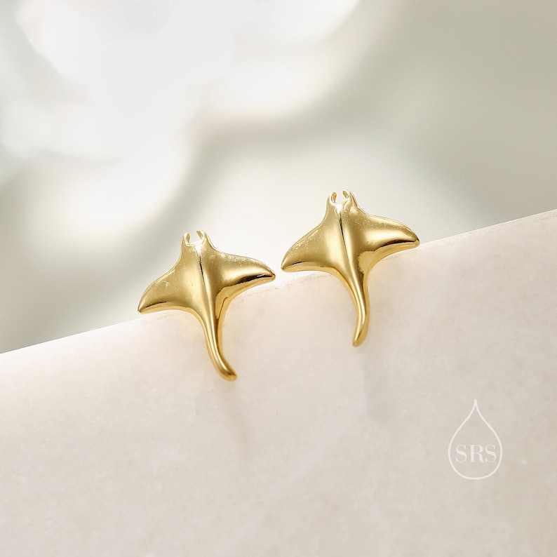 May include: A pair of gold-toned earrings shaped like stingrays. The earrings are small and delicate, and they would make a great gift for someone who loves the ocean.