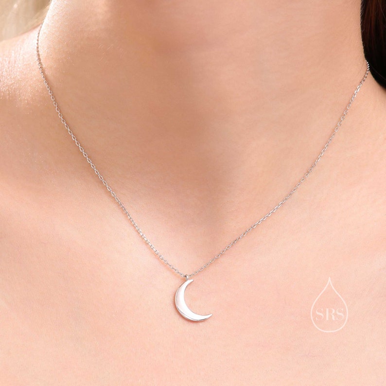 May include: A silver chain necklace with a crescent moon pendant.
