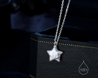 May include: A silver chain necklace with a star-shaped pendant made of iridescent white pearl. The necklace is displayed in a black velvet box with a gold-colored logo that says "SRS".