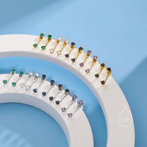 Peut inclure: Un ensemble de 12 paires de boucles d'oreilles avec des pierres précieuses de différentes couleurs. Les boucles d'oreilles sont en or et en argent et présentent une petite barre avec une pierre précieuse à chaque extrémité. Les pierres précieuses sont de différentes couleurs, notamment le vert, le bleu, le noir et le violet.