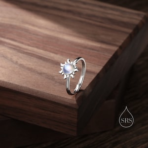 Puede incluir: Un anillo de plata con una piedra de luna engastada en un dise&ntilde;o de sol.
