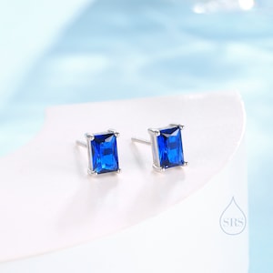 May include: A pair of silver stud earrings with square blue gemstones.