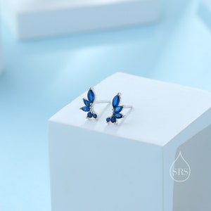 Può includere: Un paio di orecchini a lobo in argento con accenti di pietre preziose blu. Gli orecchini presentano un gruppo di piccole pietre preziose a forma di marquise disposte a forma di foglia.
