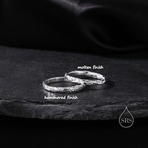 May include: Two silver rings with distinct textures. One ring features a molten finish with an irregular, flowing surface, while the other ring displays a hammered finish with small, indented marks across the band. Both rings are metallic silver.