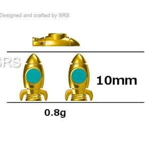 May include: Two gold-colored rocket ship charms with teal blue windows. The charms are 10mm in size and weigh 0.8 grams. The text "SRS" is visible in the image.