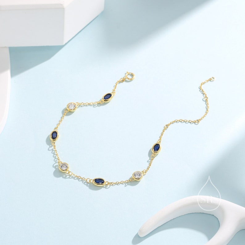Peut inclure: Un bracelet en cha&icirc;ne dor&eacute;e avec des pierres ovales bleues et claires altern&eacute;es.