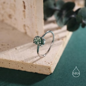 May include: A silver ring with a green moss agate oval stone.