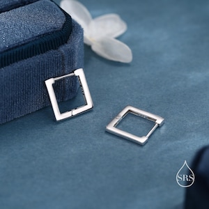 May include: A pair of silver square hoop earrings. The earrings are simple and elegant, and they would be a great addition to any jewelry collection.