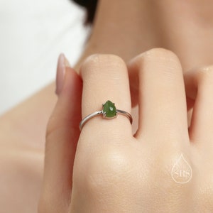Op de afbeelding: Een zilveren ring met een druppelvormige groene edelsteen.