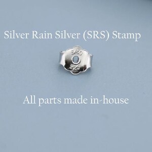 May include: A close-up of a silver earring back with the text "Silver Rain Silver (SRS) Stamp" and "All parts made in-house" on a light blue background. The earring back has a floral design.