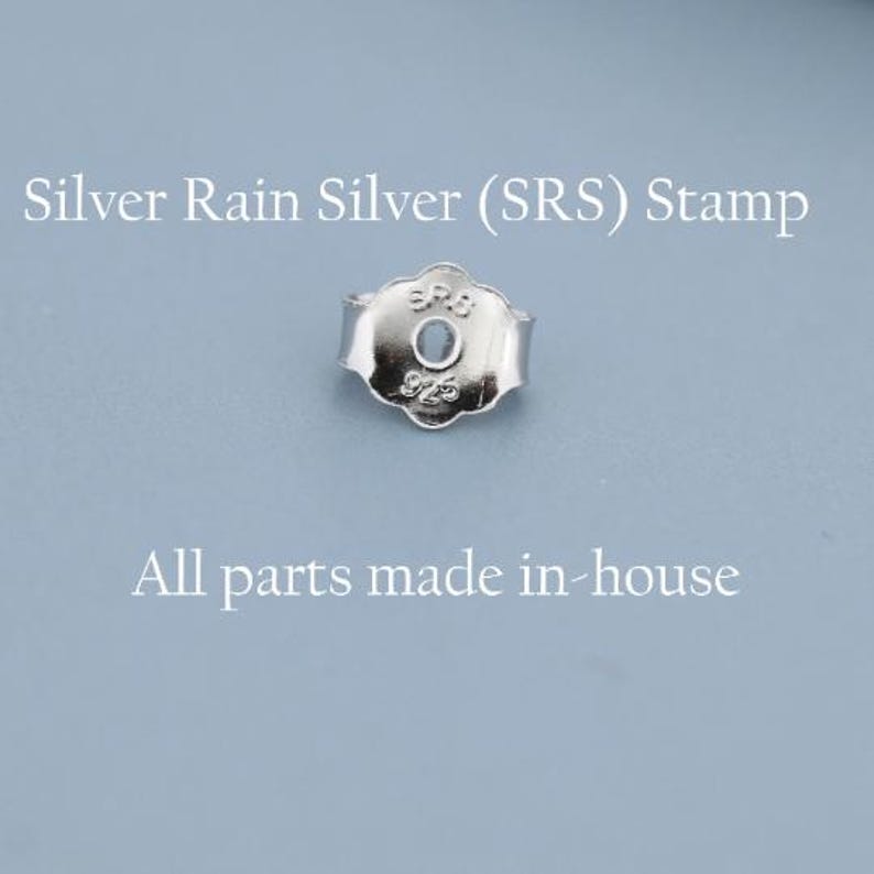 May include: A close-up of a silver earring back with the text "Silver Rain Silver (SRS) Stamp" and "All parts made in-house" on a light blue background. The earring back has a floral design.