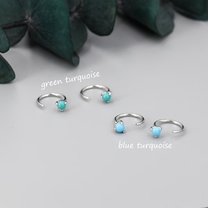 May include: Two pairs of silver hoop earrings with turquoise stones. The top pair has green turquoise stones and the bottom pair has blue turquoise stones. The text "green turquoise" is above the top pair and "blue turquoise" is below the bottom pair.