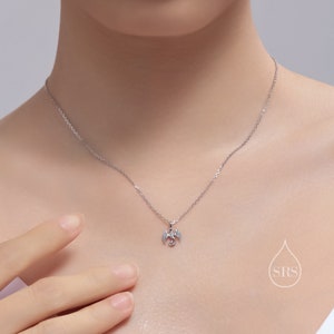 May include: A silver necklace with a small dragon pendant. The dragon is facing to the right with its wings spread out.