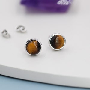 Puede incluir: Un par de pendientes de botón de plata con piedras redondas de ojo de tigre.