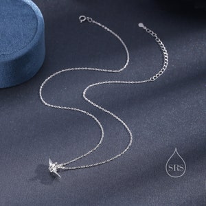 May include: A silver chain necklace with a small origami crane pendant.