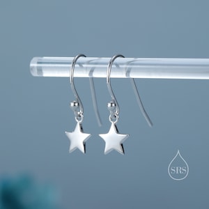 May include: A pair of silver star-shaped dangle earrings with a small bead at the top of each earring.