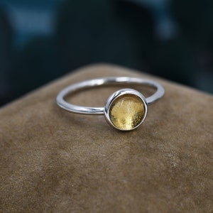 Puede incluir: Un anillo de plata con una piedra redonda de vidrio amarillo.