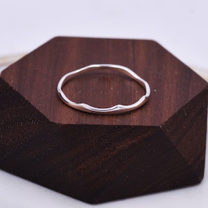 May include: A thin silver ring with a wavy, irregular edge.