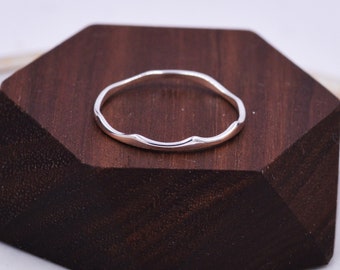 Peut inclure: Une fine bague en argent avec un bord ondulé et irrégulier.
