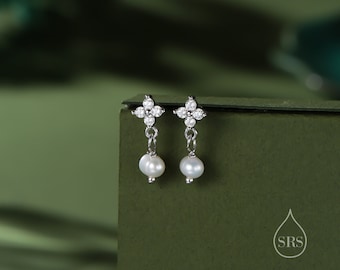 May include: A pair of silver earrings with a small pearl dangling from each. The earrings feature a four-pointed star design with clear cubic zirconia stones.