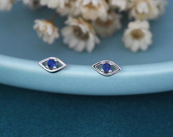 May include: A pair of silver earrings with a blue evil eye design. The earrings are small and delicate.