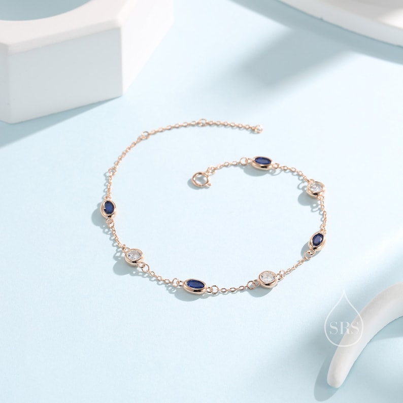 Peut inclure: Un bracelet d&eacute;licat en cha&icirc;ne dor&eacute;e avec des pierres ovales bleues et claires altern&eacute;es.