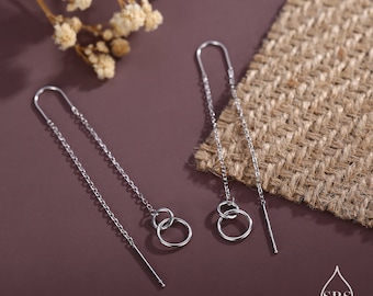Può includere: Un paio di orecchini pendenti in argento con due cerchi collegati alla base di ogni orecchino.