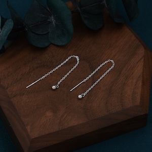 May include: A pair of silver chain earrings with small ball accents at the end of each chain.