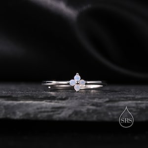 May include: A silver ring with four small white opal stones set in a flower shape.
