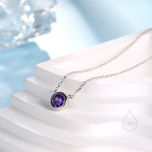 May include: A silver chain necklace with a small, round, purple gemstone pendant.