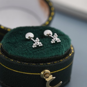 Op de afbeelding: Een paar zilveren oorbelletjes met een driehoekig ontwerp gemaakt van kleine kralen. De oorbelletjes zitten in een groene fluwelen doos.