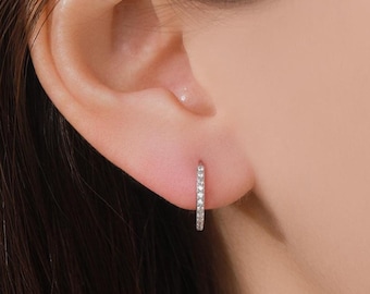 Puede incluir: Primer plano de una oreja con un pequeño aro de plata con pequeños diamantes.