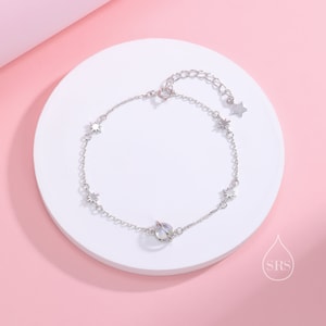 May include: A silver chain bracelet with a small, clear orb charm and star charms. The bracelet has an adjustable clasp.