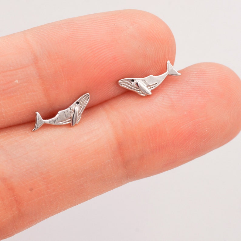 May include: A pair of silver whale stud earrings. The whales are facing the same direction and have a detailed design.