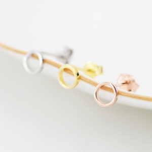 May include: Three simple hoop earrings in silver, gold, and rose gold. The earrings are small and delicate, perfect for everyday wear.