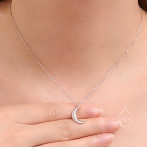 May include: A silver crescent moon pendant necklace on a delicate silver chain.